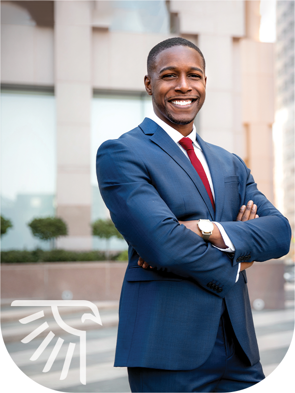 A smiling, arms-crossed, businessman standing outside in a suite
